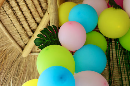 Zoom sur une monstera artificielle placée dans l'arche de ballons verts, jaunes, roses clairs, roses fuchsia et bleus turquoise. 